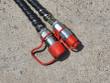 Two hydraulic hoses with red-capped flat-face quick couplers