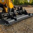 Wolverine land leveler on a JCB skid steer, teeth and leveling blades grading a gravel drive