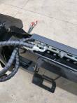 4-in-1 bucket quick-attach plate with sleeved hoses and red-capped hydraulic quick couplers