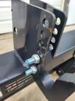 Adjustable top-link bracket on the black hitch adapter, column of holes and zinc bolts