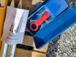 Open blue tool box with wrenches and a nitrogen charging device, hydraulic breaker operating manual alongside