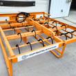 Orange hay accumulator grapple, four rows of curved bale hooks over an open steel frame, Chupp Industrial name bar