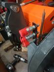 Three-coupler auxiliary bracket with red dust caps bolted to a mini skid steer loader arm