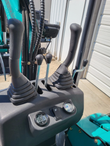 QK16R mini excavator controls: twin joysticks, travel levers, digital voltmeter and light switch