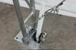 Galvanized truss leg bolted to a steel footplate with a wire-rope tensioner and ratchet anchor