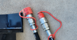 Two hydraulic hose couplers with red dust caps on the Mower King tiller's hoses, black frame edge at left