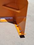 Snow blade end plate and bolted mounting bar at the corner, white poly edge running off to the left