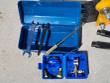 Open blue tool box with two wrenches and a drift punch, nitrogen charging kit and chisels alongside