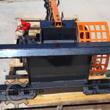 GIYI skid steer trencher: black quick-attach mount plate, orange chain boom and side shield, red-capped couplers
