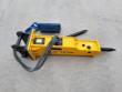 Yellow TOFT530 breaker laid flat with top-mount bracket, sleeved hoses, two chisel points and a tool box