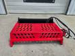 GIYI Mini Rock Rake, red frame and black tine trough with a hydraulic hose bundle coiled at the corner