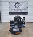 Rotating grapple front view: hydraulic rotator, coiled hose lines and toothed jaws with an orange grip pad