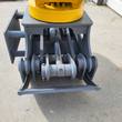 Gray grapple jaw pivots and chrome hydraulic cylinder rod under the yellow rotator, seen from the front