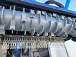 Gray steel drum rotor with bolted cutting teeth on the Raytree mulcher, row of chain guard links hanging below