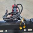 Hydraulic hoses with flat-face quick couplers and yellow dust caps coiled on the breaker's skid steer mount plate