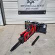 Red Raytree hydraulic breaker with pointed moil on a skid steer quick-attach plate, spare chisel bit beside it