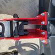 Raytree hydraulic breaker's red mounting bracket bolted to a skid steer boom, hoses and quick couplers attached