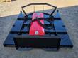 Skid steer brush cutter from the rear: universal quick-attach plate, red hydraulic motor cover, hoses and push bar