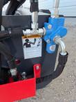 Blue hydraulic flow-divider valve on the vibratory roller, leak-hazard warning label