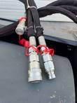 Two hydraulic quick-connect couplers with red caps for the vibratory roller's hoses