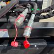Hydraulic quick-connect couplers with red dust caps on the soil conditioner