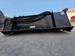 Power rake bucket's rotor drum underside, hydraulic hoses along the top and teeth at the base