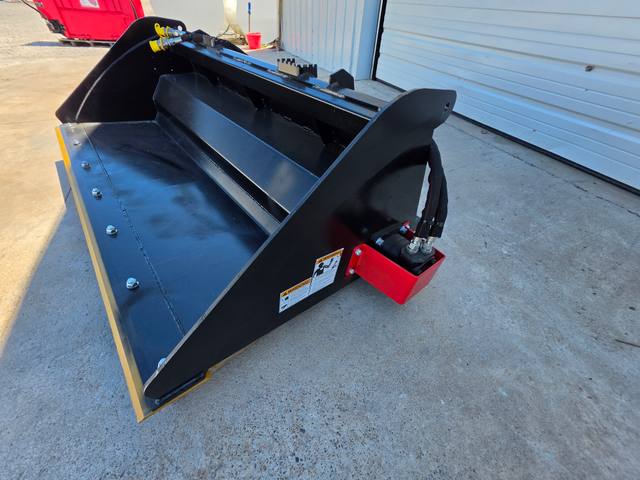 Raytree power rake bucket, drive-end view with red hydraulic motor housing, hoses, and yellow cutting edge