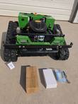 Green tracked remote control mower from the front: RATO RV225-XPro engine, LED lights, black bumper; boxes in front