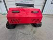 Front of the red tracked mower with two LED strobe lights, side vents and rubber tracks beneath the hood
