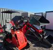 Red SDLANCH mini skid steer on rubber tracks with bucket raised, canopy overhead and cutout logo on the front panel