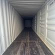 Empty container interior looking the full length, white corrugated steel walls and ceiling, dark plywood floor