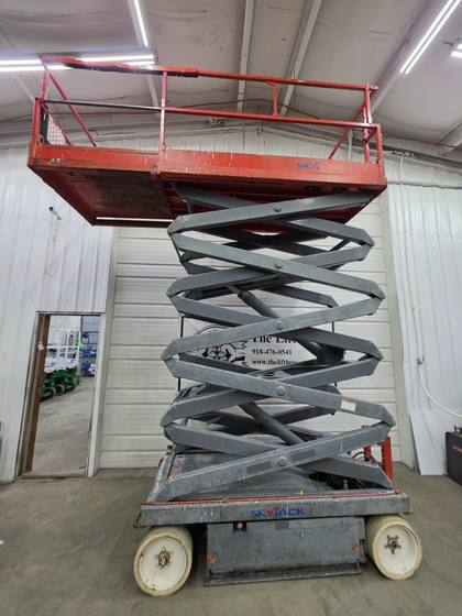 Skyjack SJIII 4632 with platform raised high, gray scissor arms fully extended, end view