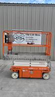 Orange Snorkel S3215L electric scissor lift, stowed, left side view in front of the Lift Bros sign