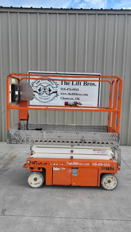 Orange Snorkel S3215L electric scissor lift, stowed, left side view in front of the Lift Bros sign