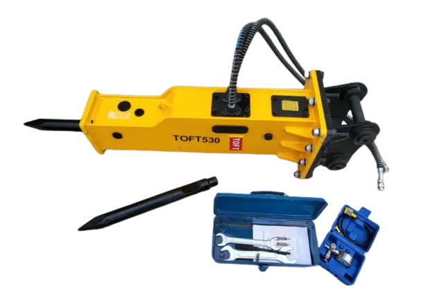 TOFT530 yellow hydraulic breaker lying flat with moil point, hoses and bracket, spare chisel, wrench and charge kit boxes