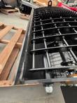 Steel grate bars and cutting teeth on a black concrete mixing bucket, resting on a wood pallet