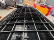 Close view of the serrated cutting teeth on the steel grate of a black concrete mixing bucket