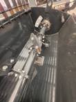 Inside of a black mixing bucket: center shaft with mixing paddles bolted on and a lifting eye on the rim