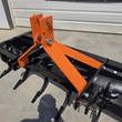 Orange 3-point hitch tower with top-link pin and linchpin, braces bolted to the ripper toolbar