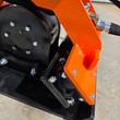 Rubber isolator mount under the orange top plate of the Wolverine E-VPC06 compactor, bolted black housing