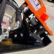 Warning decal on the orange bracket of the Wolverine E-VPC06 compactor, bolted isolator mount and motor hose