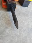 Black breaker chisel tip and tool holder block on the end of an orange hydraulic hammer