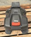 Husqvarna Auto Mower seen from above on its charging base, gray body with red-orange hatch