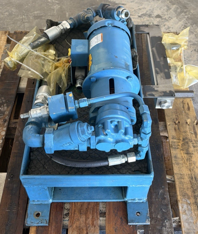 Blue hydraulic power unit on a pallet with steel tray, motor, gear pump and hoses, seen from above