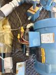 Baldor motor terminal box with yellow wire connectors and warning label beside blue hydraulic fittings