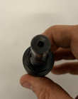 Rear end of a black expanding reamer held in a hand, with a small center hole in the shank