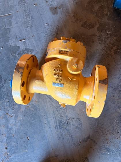 Yellow 4-inch Class 900 WCC flanged swing check valve with cast 4, 900, WCC markings and a CAM mark