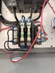 Two fuse holders and a terminal block with red and black wiring inside the motor control enclosure