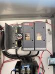 ABB disconnect switch with a rotary handle mounted on the back panel of the open enclosure above a contactor