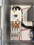 Cutler-Hammer contactor with fuse blocks and red wiring on the back panel of the open enclosure